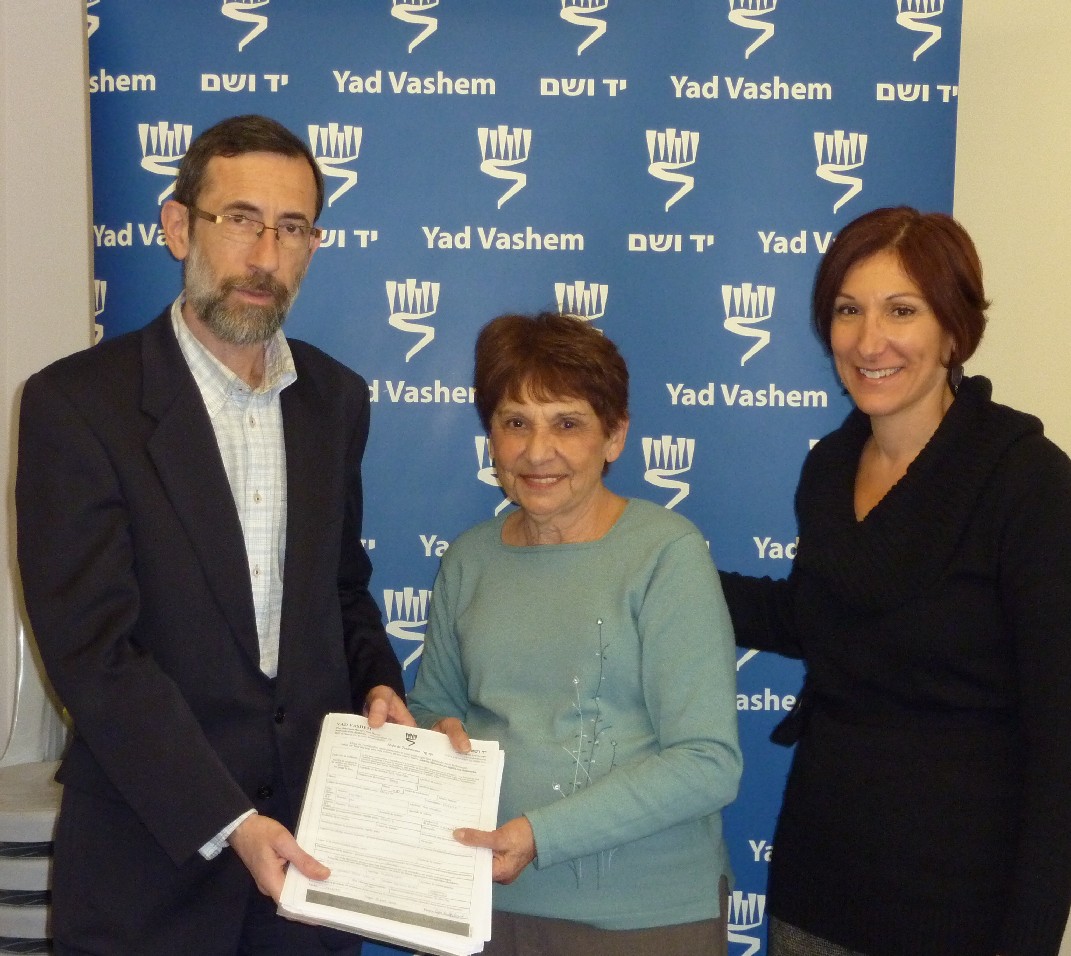 Alexander Avram (Left), director of the Hall of Names, and Cynthia Wroclawski (Right), Manager of the Shoah Victims' Names Recovery Project, receive Pages of Testimony from Amalia Miodownik (center)